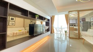 Una camera d'albergo moderna con divano, televisione e zona pranzo con sedie e tavolo.