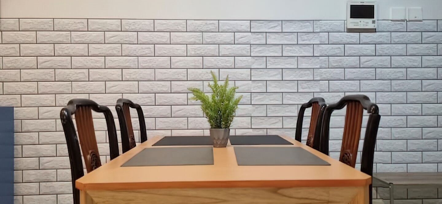A dining table with four chairs, a potted plant, and a brick-patterned wall.