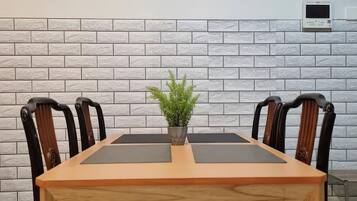 A dining table with four chairs, a potted plant, and a brick-patterned wall.