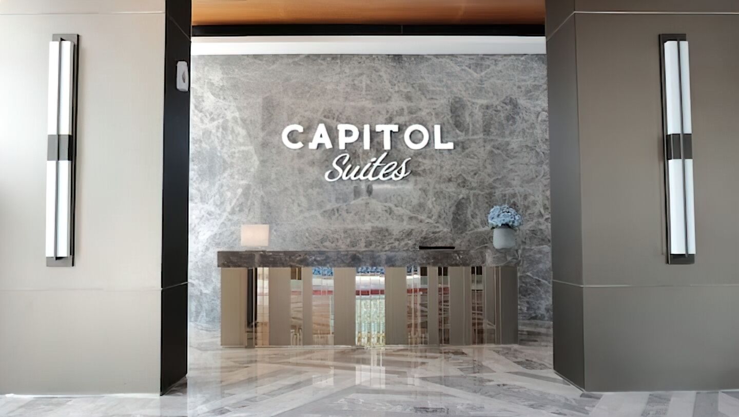 A reception area with a marble wall and a sign that reads "CAPITOL Suites".