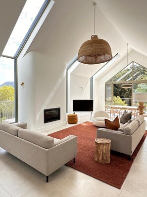 A spacious living room with a large window, a fireplace, and a dining area with a view.