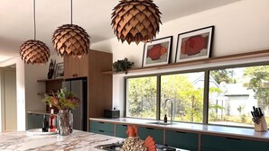 A modern kitchen with a marble island, wooden chairs, and pendant lights. - New, stylish, 3 bedroom home, with infinity pool and Table Mountain views (Cape Town)