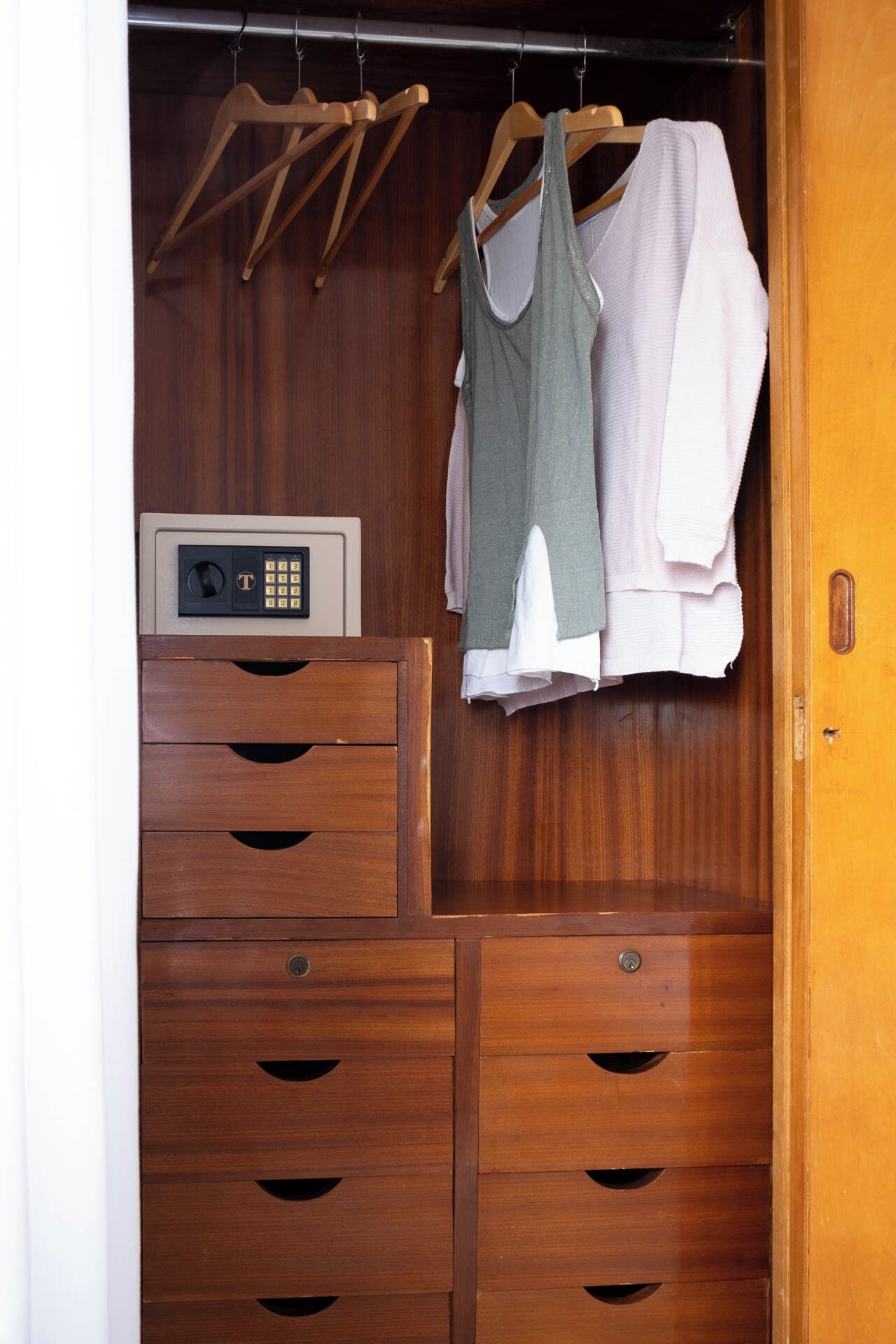 A wooden wardrobe with multiple drawers and a built-in electronic device.