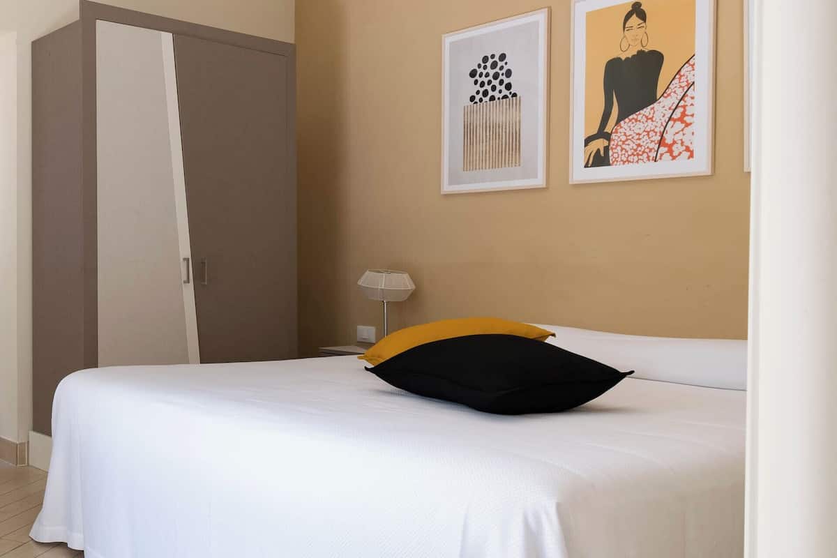 Una camera d'albergo con un letto, un armadio e due opere d'arte appese alla parete.