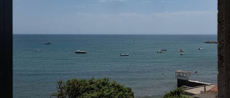 A view of a calm sea with several boats and a small dock with a lifebuoy.