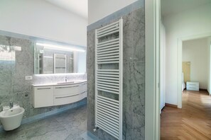 A modern bathroom with a marble backsplash, a built-in sink, and a white radiator.