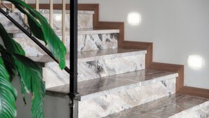 A staircase with marble steps and wooden handrails, leading to an upper floor.