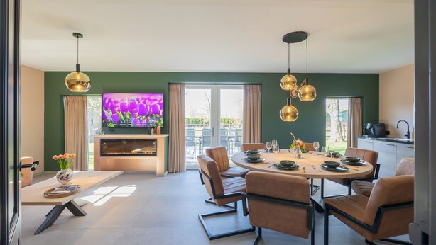 Een moderne eetruimte met een ronde tafel, lederen stoelen en hanglampen.