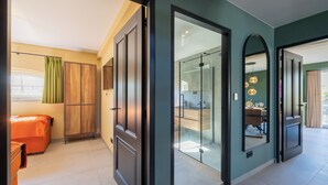Een hotelkamer met een bed, een kledingkast, een badkamer met een glazen deur en een zithoek met een tafel en stoelen.