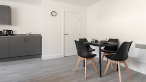 A modern kitchen with grey cabinets and a dining area with a table and four black chairs.