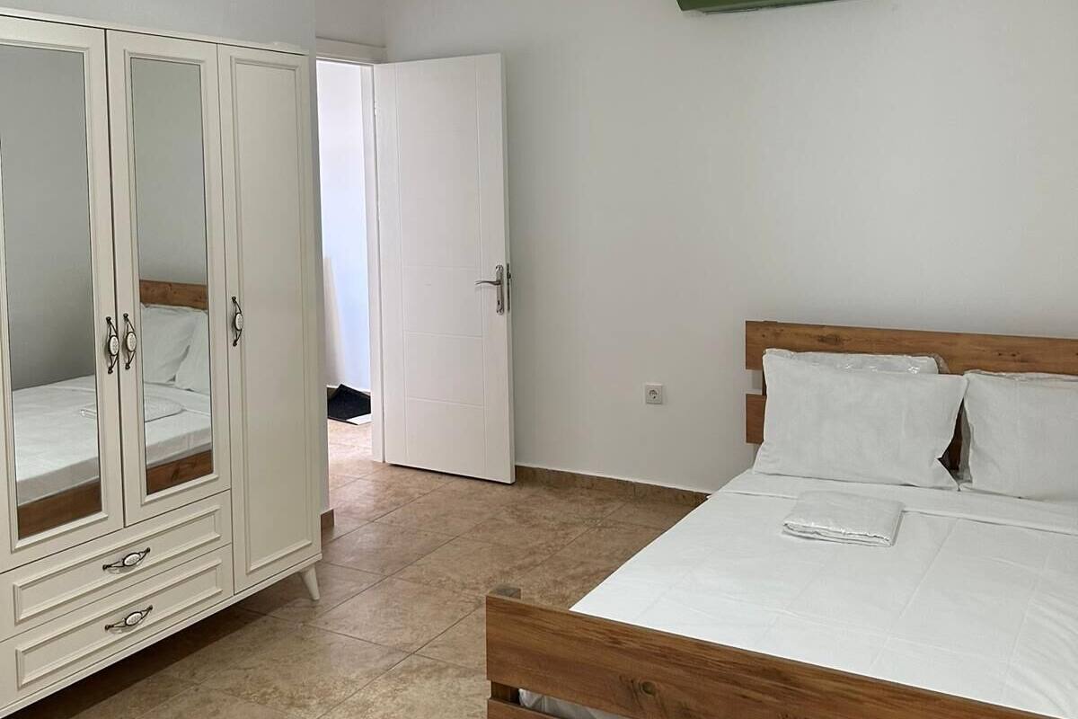 A bedroom with a wooden bed, white wardrobe, and a hanging light fixture.