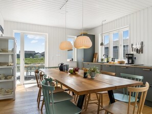 Et moderne køkken med et træbord og stole, en kaffemaskine og udsigt til det fri.