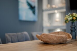 A wooden bowl on a table in a modern dining area with a blue wall and a framed picture. - Suite 3 on the Hill - Stunning, Spacious, and Breathtaking Panoramic View (Amfilochia)