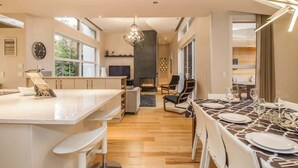 Een moderne keuken met een groot schiereiland, een eethoek met een tafel voor vier personen, en een open haard op de achtergrond.