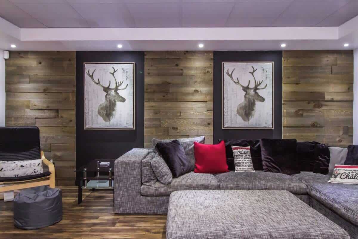 A modern living room with a grey sectional sofa, a small table, and two framed deer antlers on the wall.