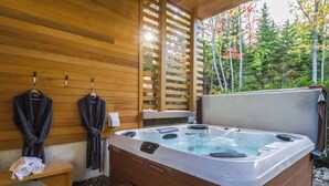 Een houten chalet met een jacuzzi, houten banken en een bank met handdoeken.