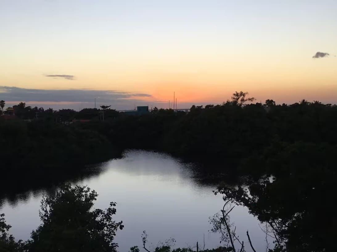 Ein friedlicher See bei Sonnenuntergang mit Bäumen und ruhiger Wasseroberfläche.