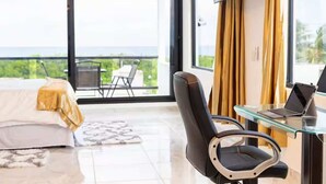 Une chambre d’hôtel moderne équipée d’un lit, d’un bureau avec un ordinateur portable, d’une chaise et d’un téléviseur fixé au mur.