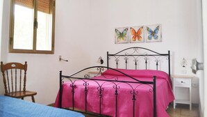Un dormitorio con cama, una silla, un escritorio y una ventana con persianas.