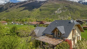 Una casa con techo inclinado, un balcón y vista a una cordillera.