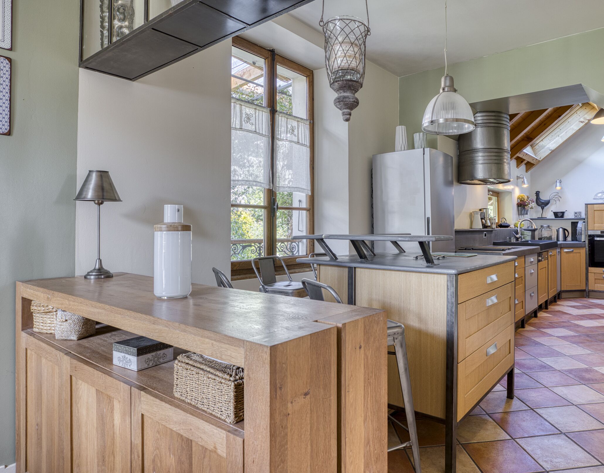 A modern kitchen with wooden cabinets, a central island, and pendant lighting.