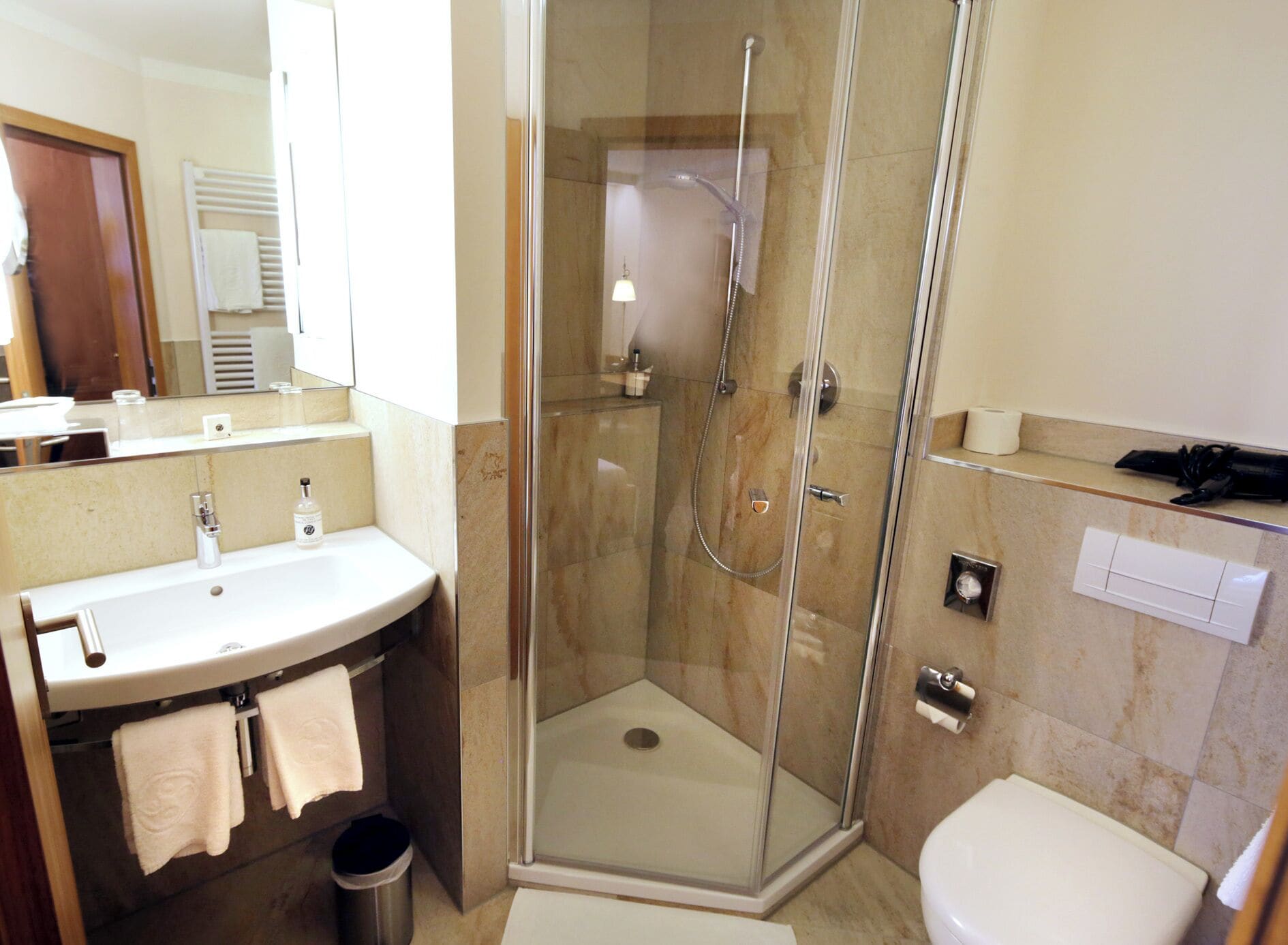 Ein modernes Badezimmer mit einer Duschkabine, einem Waschbecken mit Spiegel und einer Toilette.