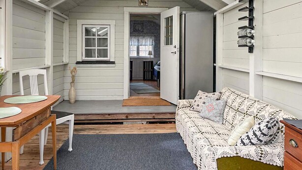 A cozy room with a wooden table, a white sofa, and a door leading to another room. - 1 bedroom gorgeous home in Romakloster (Romakloster)