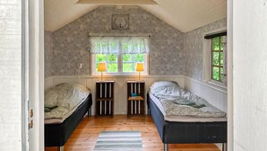 A small, cozy room with two single beds, a window with a view of greenery, and a ceiling light fixture. - 1 bedroom gorgeous home in Romakloster (Romakloster)