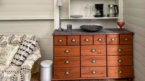 A wooden dresser with multiple drawers, a lamp, and a shelf with kitchen items. - 1 bedroom gorgeous home in Romakloster (Romakloster)