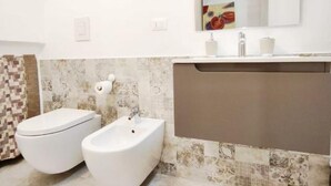Un baño con inodoro, bidé y lavabo con espejo.