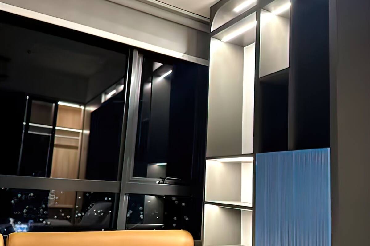 Interior de un vagón de tren con cama, ventana y estantería.