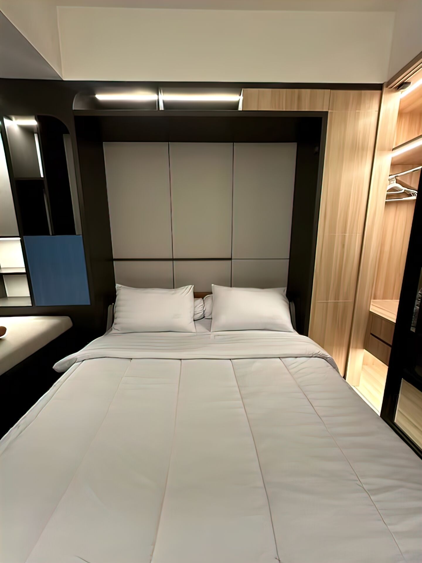 Une chambre d’hôtel moderne avec un grand lit, une table de chevet et une armoire intégrée.