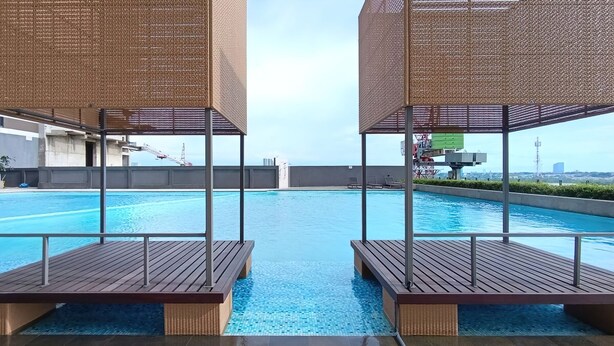 Una piscina en la azotea con sillas de madera y vistas al horizonte de la ciudad.