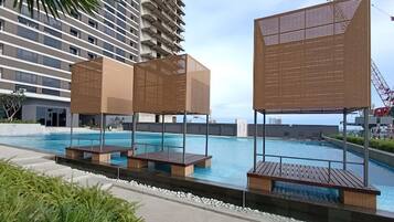 Relax by the ocean-view pool surrounded by a deck with benches and a geometric structure.