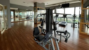A spacious gym with cardio machines, weight stations, and a large mirror. - Samara Suites by Emily in Jakarta (Jakarta)