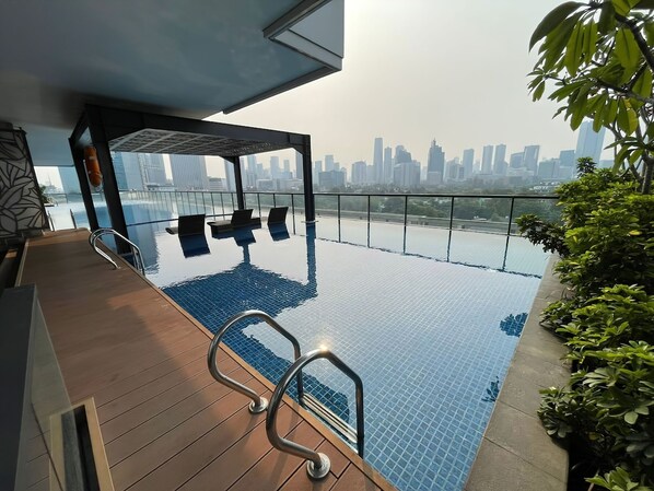 Enjoy breathtaking city views from our rooftop infinity pool, surrounded by a deck and lounge chairs.