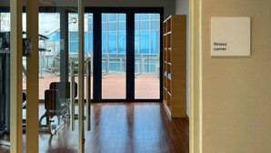 A modern fitness center with a wooden floor, large windows, and exercise equipment. - Samara Suites by Emily in Jakarta (Jakarta)