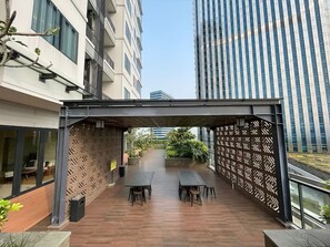Enjoy al fresco dining on this outdoor terrace with tables and chairs, surrounded by lush greenery and city views.
