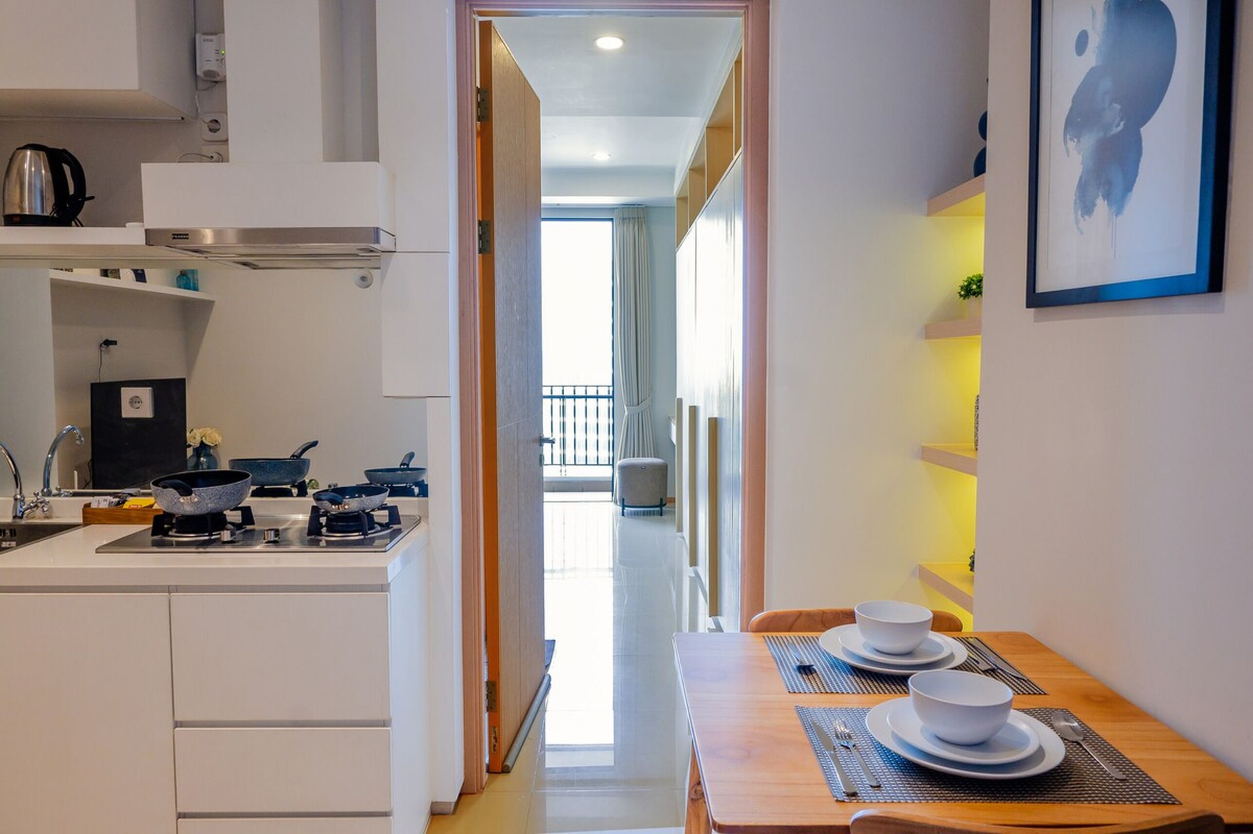 Una cocina moderna con armarios blancos, una estufa y un comedor con una mesa preparada para dos.