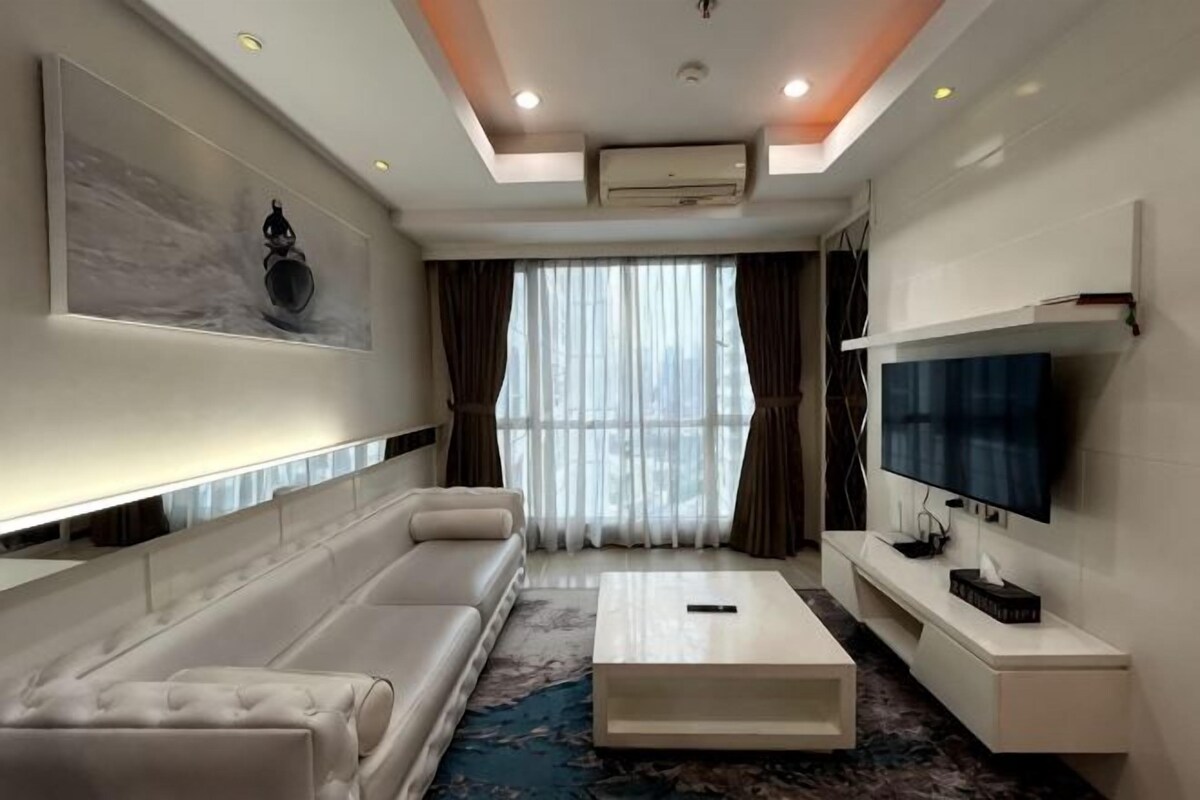A modern living room with a sofa, coffee table, TV, and artwork on the wall.