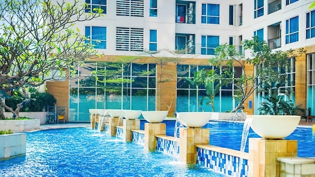 A swimming pool with multiple lanes, surrounded by a building with large windows and a tiled floor. - Casa Grande Residence (Jakarta)