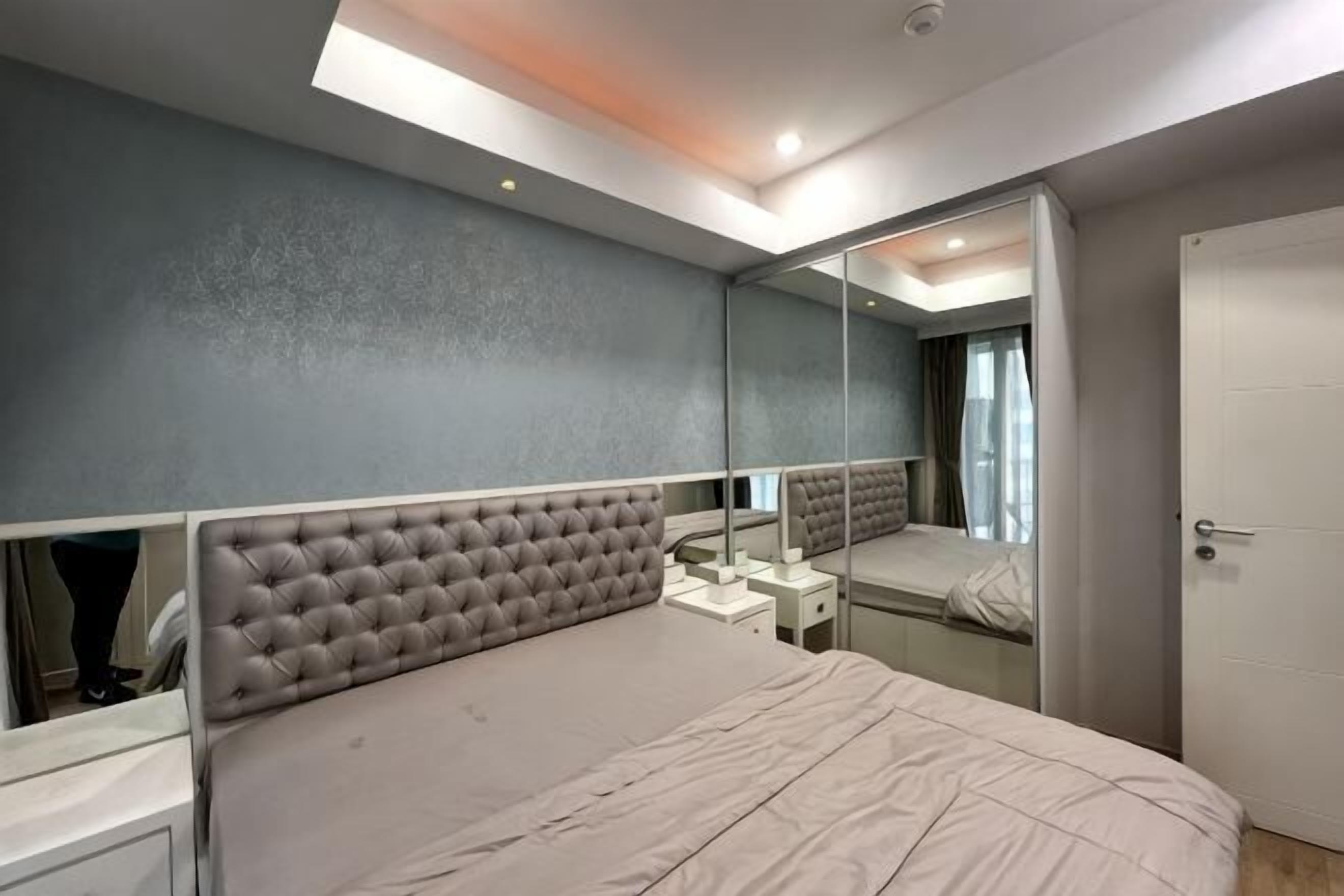 Une chambre avec un grand lit, un miroir, une armoire et une porte.