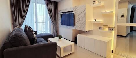 Een moderne woonkamer met een bank, salontafel en een televisie bevestigd aan een marmeren muur.