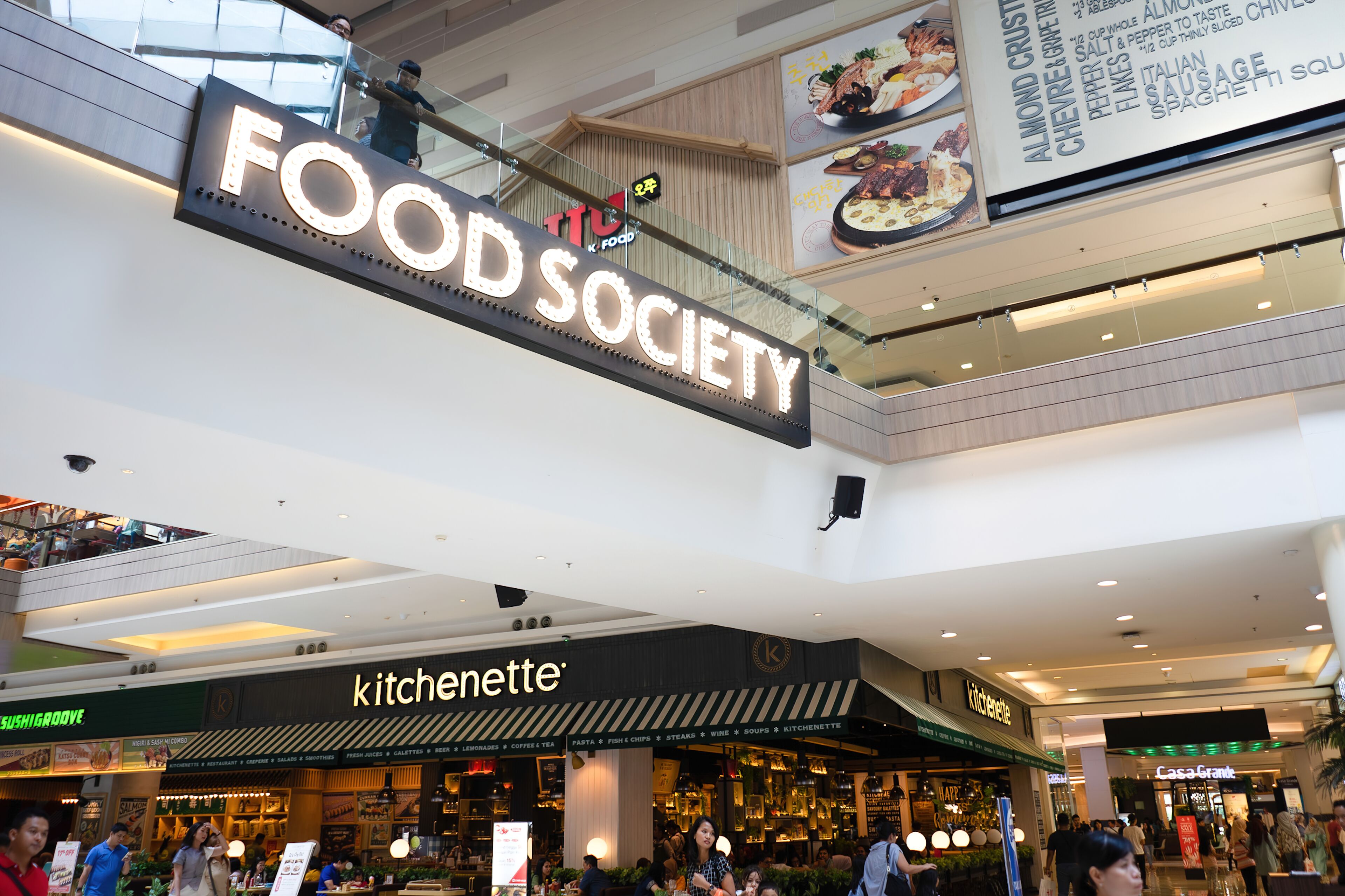 Ein Food-Court mit einem auffälligen Schild für 'FOOD SOCIETY' und einem Restaurant, das eine Küchenzeile bietet.