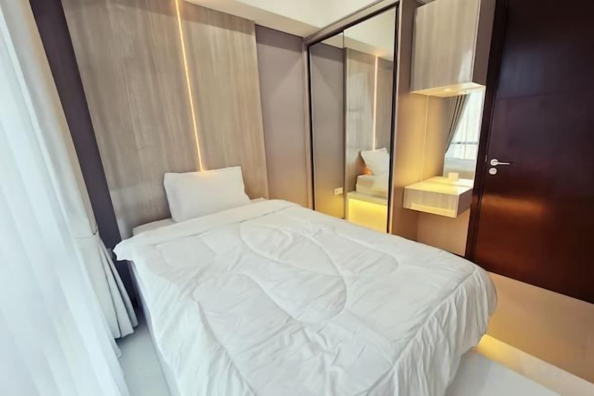 A modern bedroom with a bed, bedside table, and a mirror.