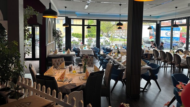 An indoor dining area with tables set for two, large windows, and hanging pendant lights. - HOTEL BONÉ TO (Salzgitter)