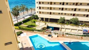 A hotel with a pool area, a beach view, and a multi-story building.