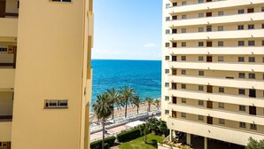 A high-rise hotel with multiple balconies overlooking a beach and the sea.
