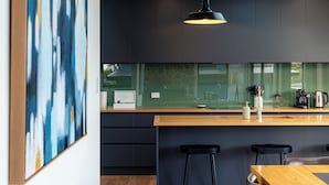 Eine moderne Küche mit dunklen Schränken, einer Holz Arbeitsplatte und schwarzen Barhocker.
