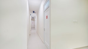 A narrow, white-walled hallway with a door marked 'G1' and a light switch. - Hotel O Krekot Residence Pasar Baru (Jakarta)